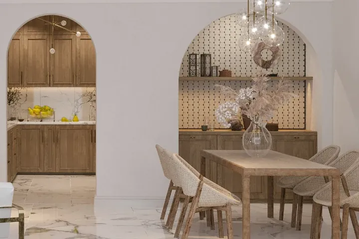 A dining table beside arched openings to the kitchen and a display niche